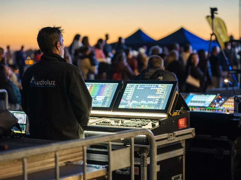 Operador técnico frente a la consola de luces y sonido durante un evento al atardecer